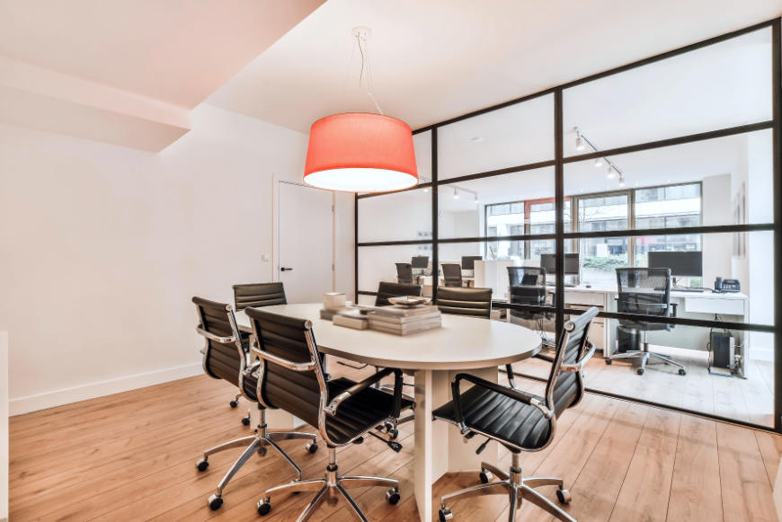 Interior de oficina con cerramiento de cristal tipo industrial y lámpara colgante roja
